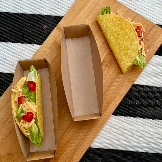 Two filled tacos on a wooden board with a striped background