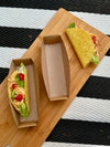 Two filled tacos on a wooden board with a striped background
