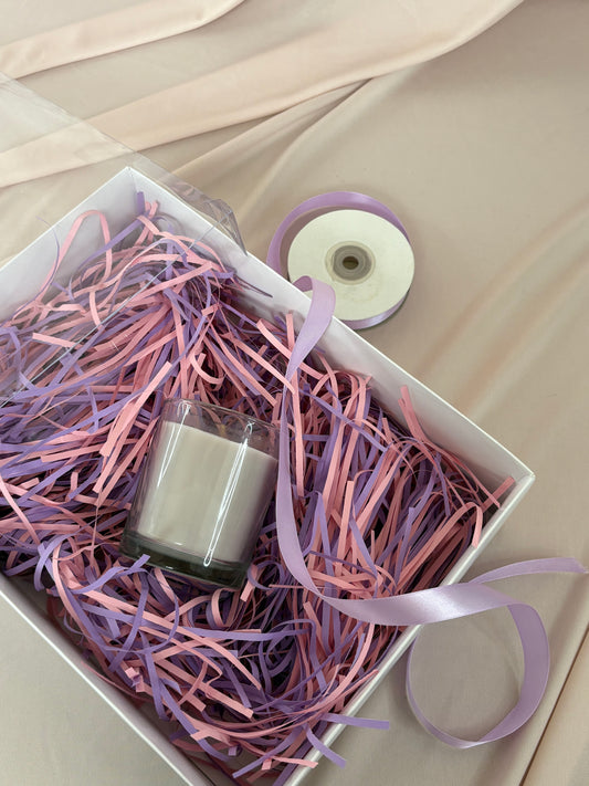 Nail polish bottle in a box with pink and purple shredded paper and ribbons.