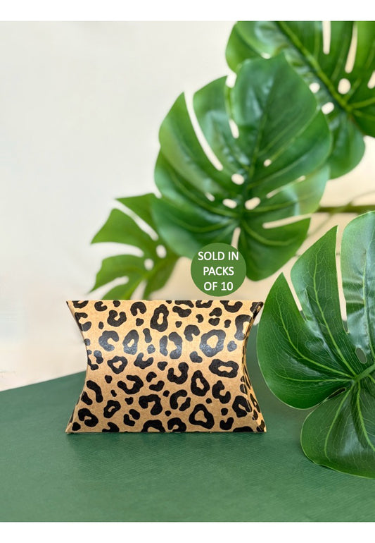 Leopard print pillow on a green surface with leaves in the background
