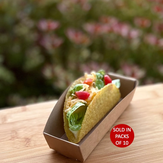 Taco in a cardboard container on a wooden surface with a blurred natural background
