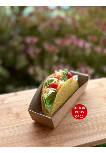 Taco in a cardboard container on a wooden surface with a blurred natural background
