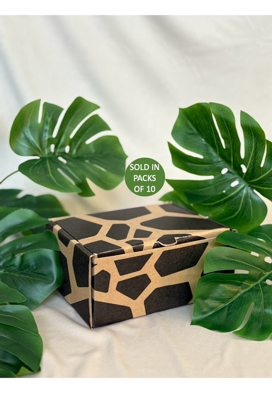 Box with geometric pattern surrounded by green leaves on a light background
