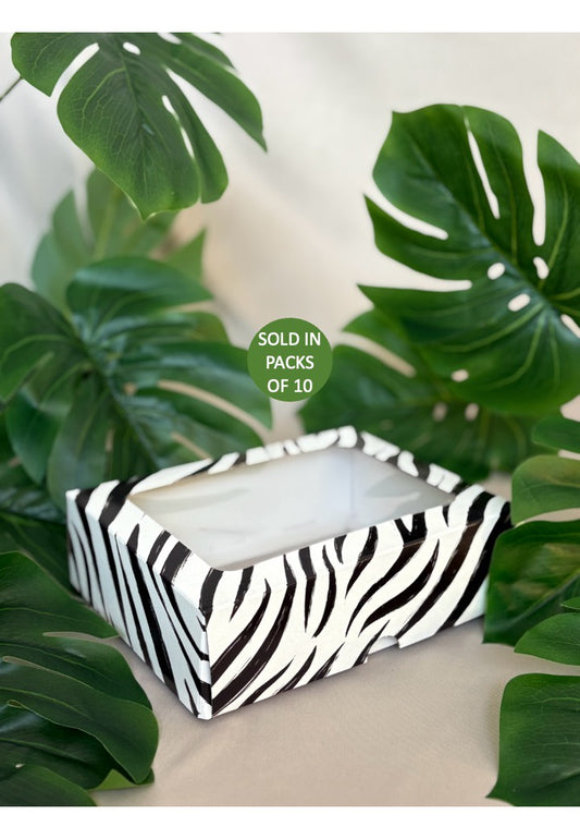Tissue box with zebra pattern on a white surface with green leaves in the background