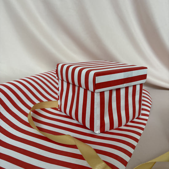 Red and white striped fabric with a gold ribbon on a beige background