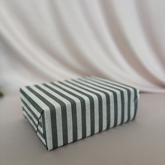 Rectangular box with black and white striped pattern on a light background
