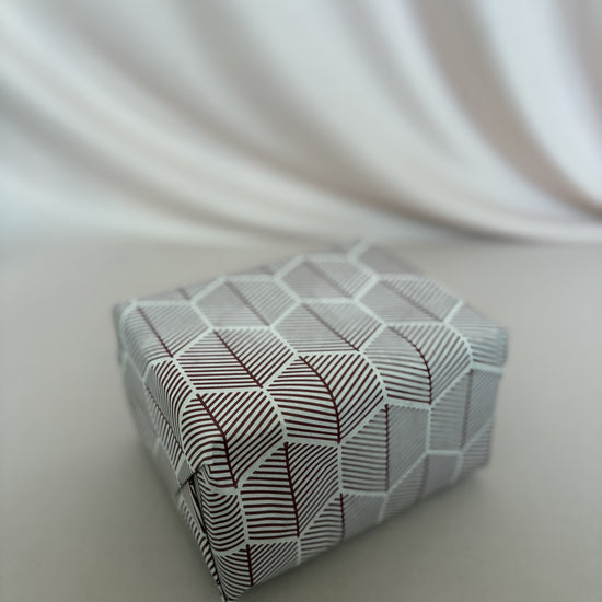 Small rectangular box with geometric pattern on a white fabric background