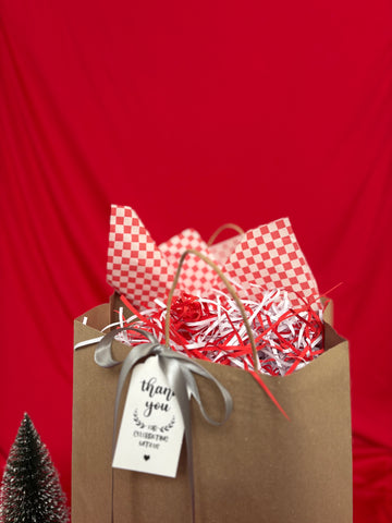 Gift bag with red and white checkered paper, red and white shredded paper, and a 'thank you' tag on a red background.