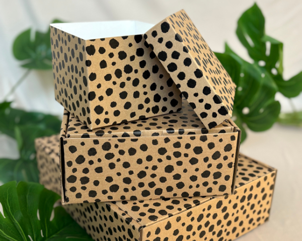 Stack of cardboard boxes with cheetah print design on a neutral background