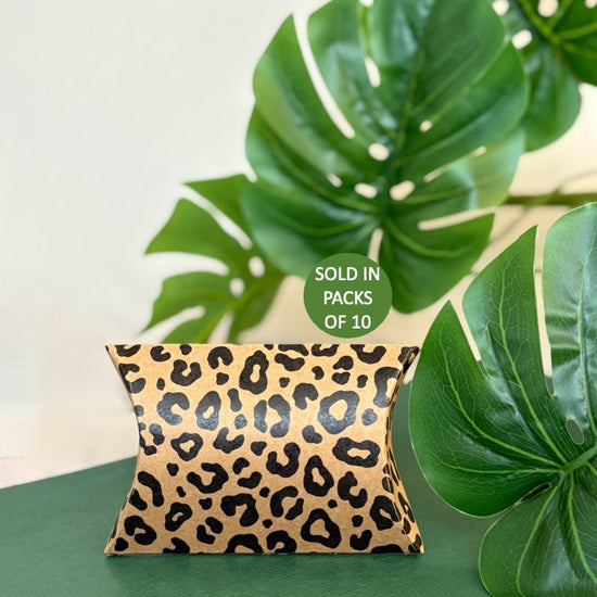 Leopard print pillow on a green surface with leaves in the background