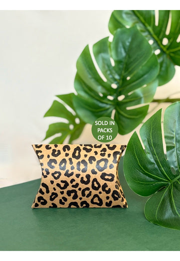 Leopard print pillow on a green surface with leaves in the background