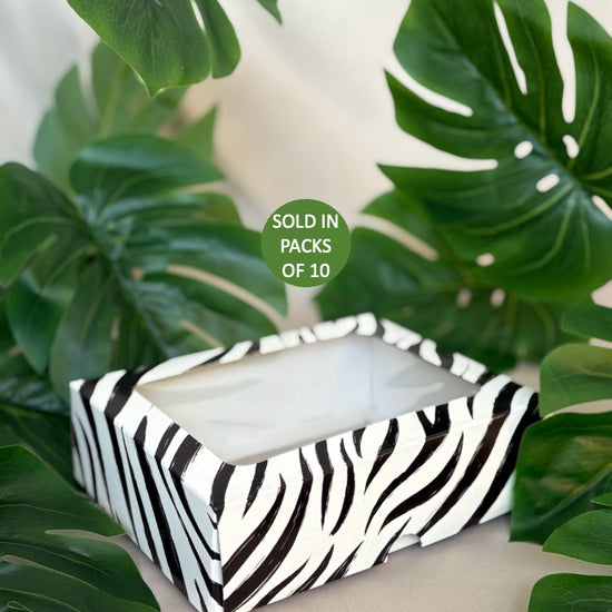 Tissue box with zebra pattern on a white surface with green leaves in the background